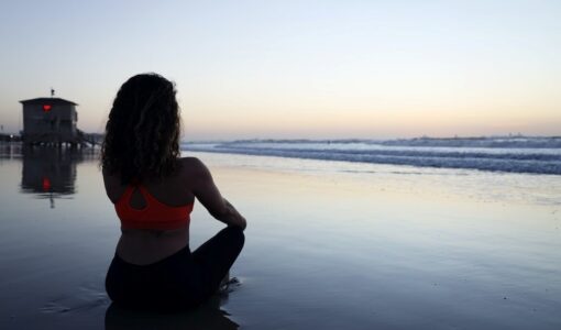 women meditating on a sandy beach